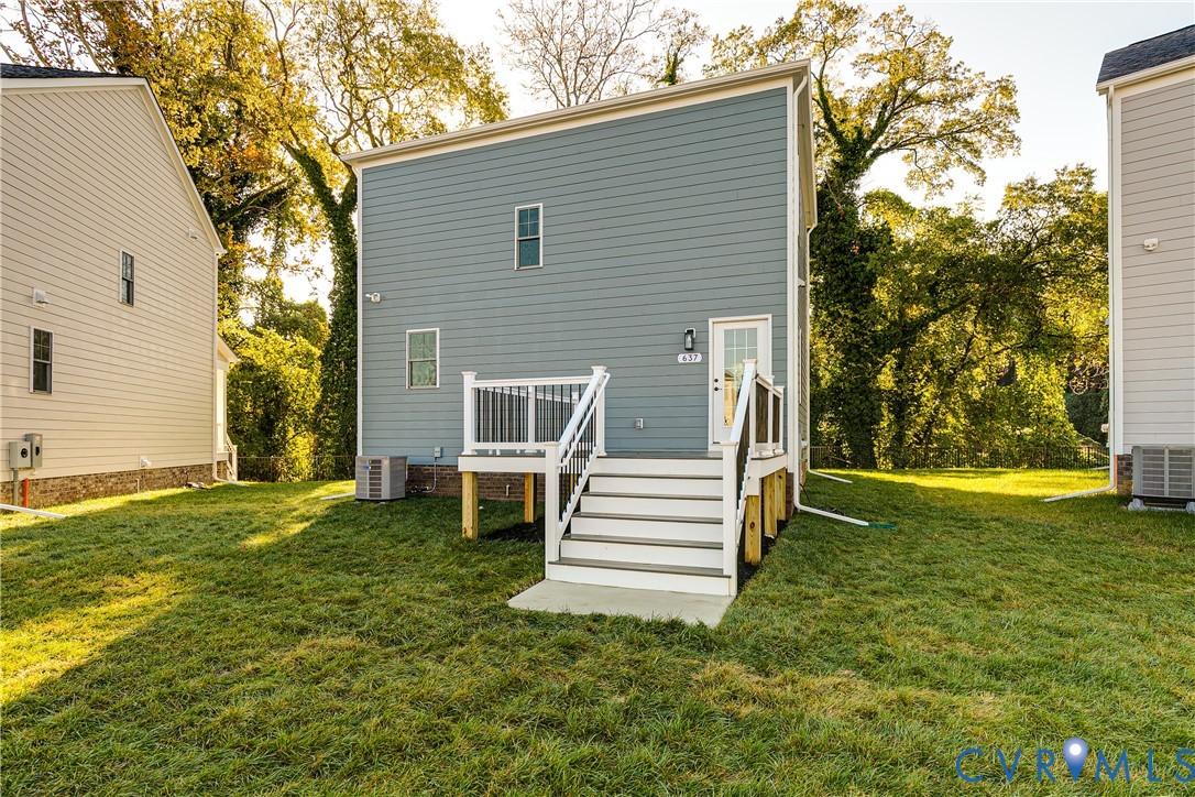 Exterior elevation featuring horizontal lap siding, a raised deck with white railings, a concrete landing, and a grass-covered lot