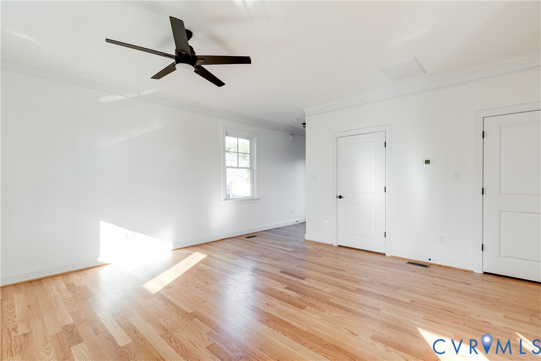 Interior space featuring wood-finish flooring, a matte black ceiling fan, crown molding, and two-panel interior doors