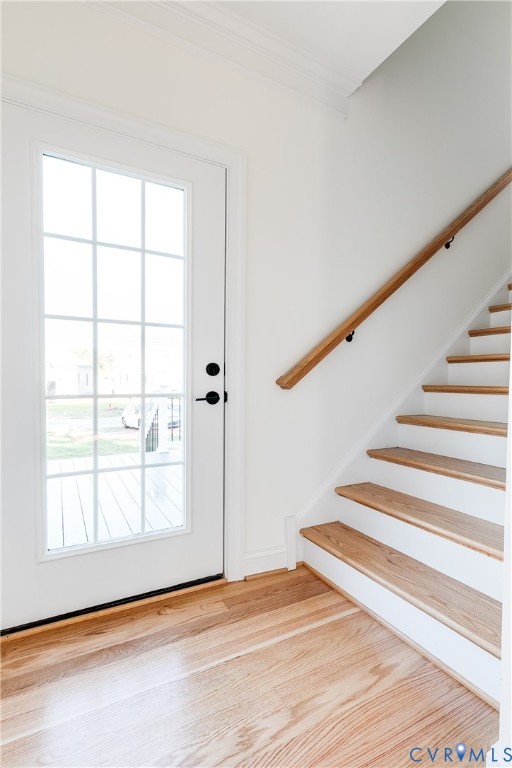 Entryway featuring a full-light glass panel door with matte black hardware, wood-finish flooring, and a staircase with wood treads and a matching wood handrail