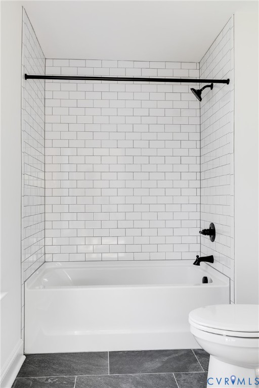 Tub and shower combination featuring white subway tile surround, matte black plumbing fixtures, and dark-toned floor tile