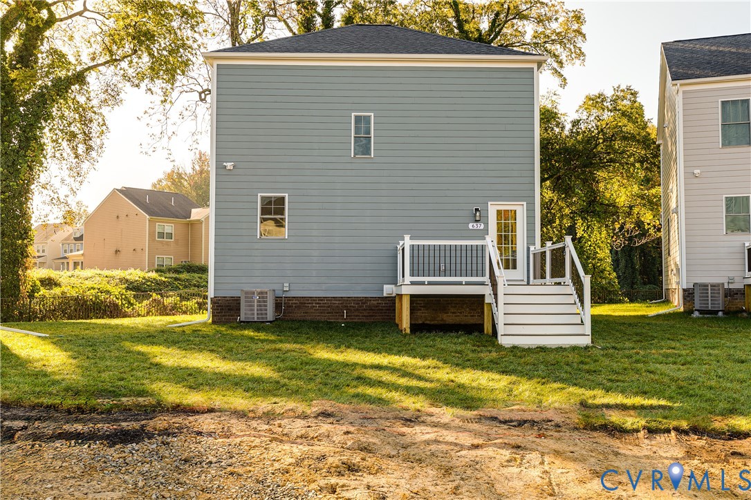 Two-story residence featuring light blue horizontal siding, a masonry foundation, and an elevated deck with white railings and stairs