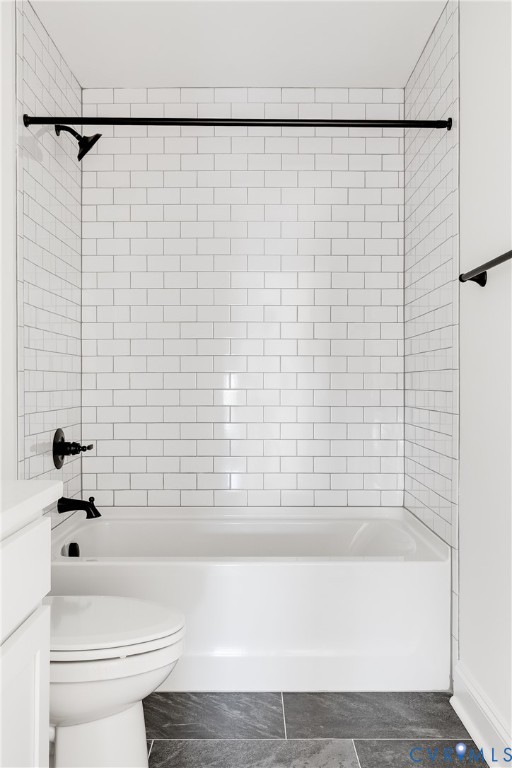 Bathtub shower combination featuring white subway tile surround, matte black hardware, and dark stone-finish floor tile