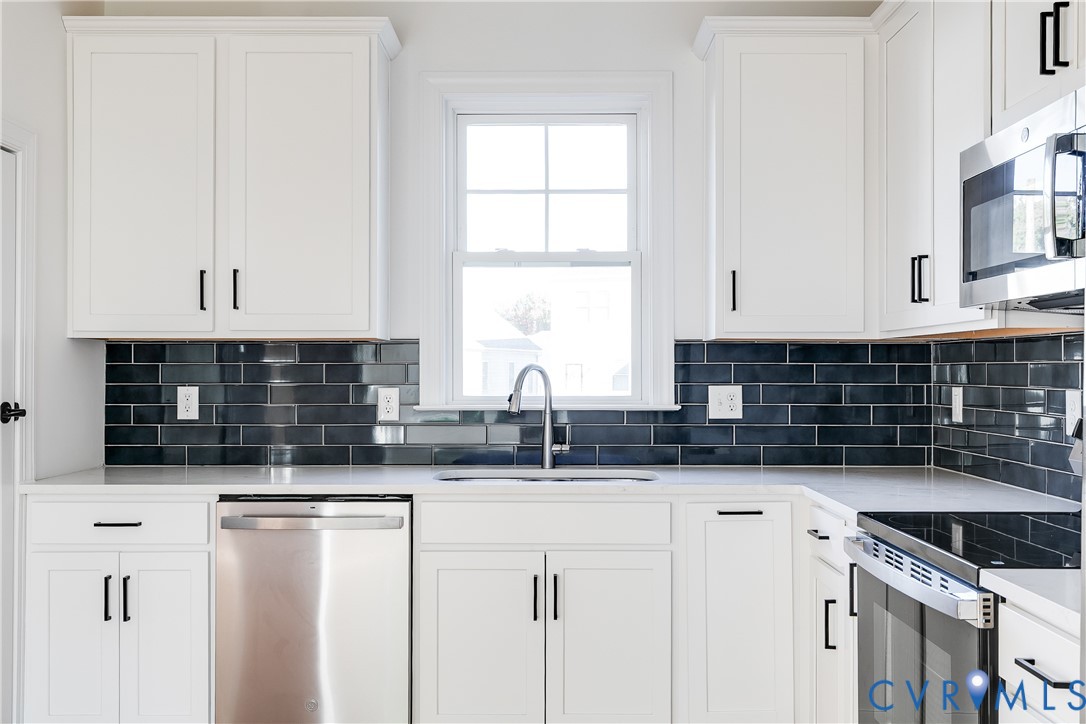 Kitchen featuring white shaker-style cabinetry, dark subway tile backsplash, stainless steel appliances, neutral countertops, and a single-basin sink with a gooseneck faucet