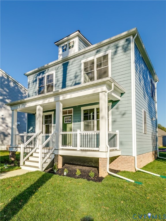 Two-story residence featuring lap siding, a front porch with square columns and metal railing, a dormer window, and a stone-veneer foundation
