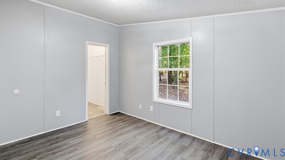 Neutral-toned paneling, wood-finish flooring, multi-pane window, and walk-in storage area