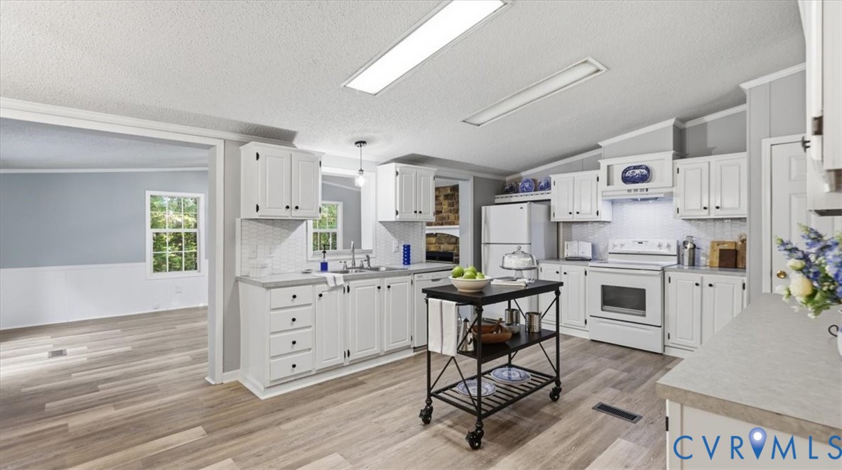 Kitchen featuring white cabinetry, wood-finish flooring, tiled backsplash, and recessed overhead lighting Kitchen featuring white cabinetry, wood-finish flooring, tiled backsplash, and recessed overhead lighting