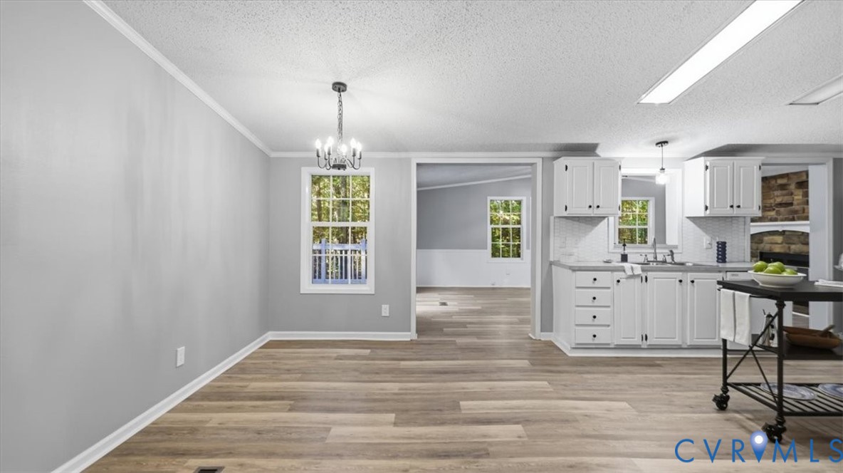 Interior space featuring wood-finish flooring, white cabinetry, a multi-light chandelier, and expansive windows