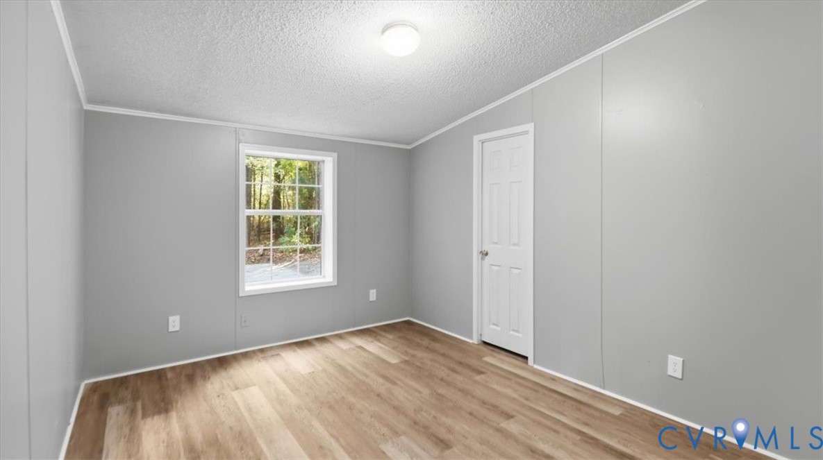 Neutral-toned wall panels, wood-finish flooring, single-hung window with muntins, and a flush-mount ceiling light fixture