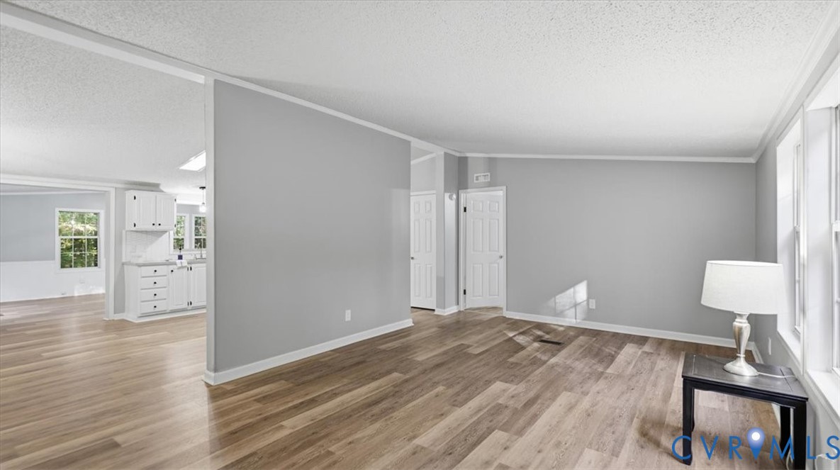 Living area featuring wood-finish flooring, neutral wall tones, multi-panel interior doors, and crisp white trim