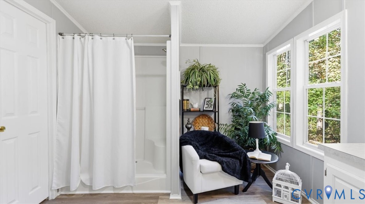 Shower stall with white surround, multi-pane windows, and wood-finish flooring