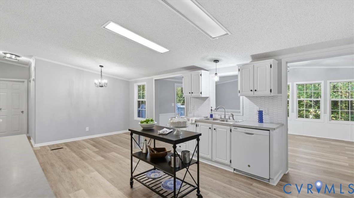 Kitchen featuring white cabinetry, textured tile backsplash, stainless steel sink with goose-neck faucet, and wood-finish flooring Kitchen featuring white cabinetry, textured tile backsplash, stainless steel sink with goose-neck faucet, and wood-finish flooring