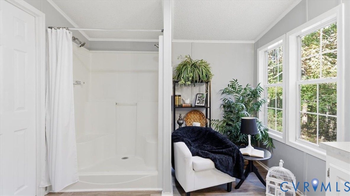 White walk-in shower enclosure featuring an integrated corner seat, polished chrome fixtures, neutral wall color, and double-pane windows