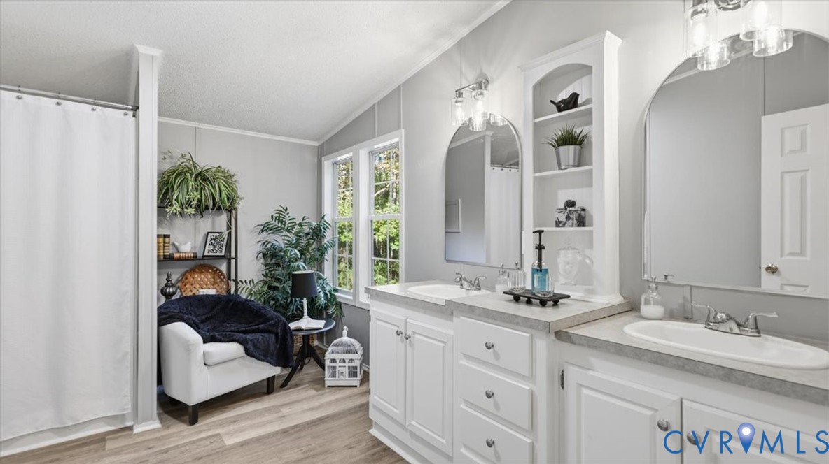 Double vanity featuring white cabinetry, stone-finish countertops, undermount oval sinks, arched mirrors, and integrated shelving