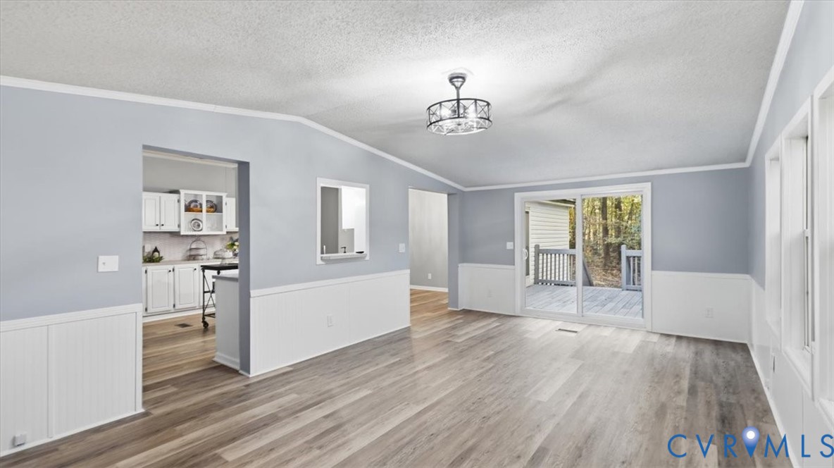 Interior space featuring wood-finish flooring, white wainscoting, a drum-style ceiling light fixture, and sliding glass doors