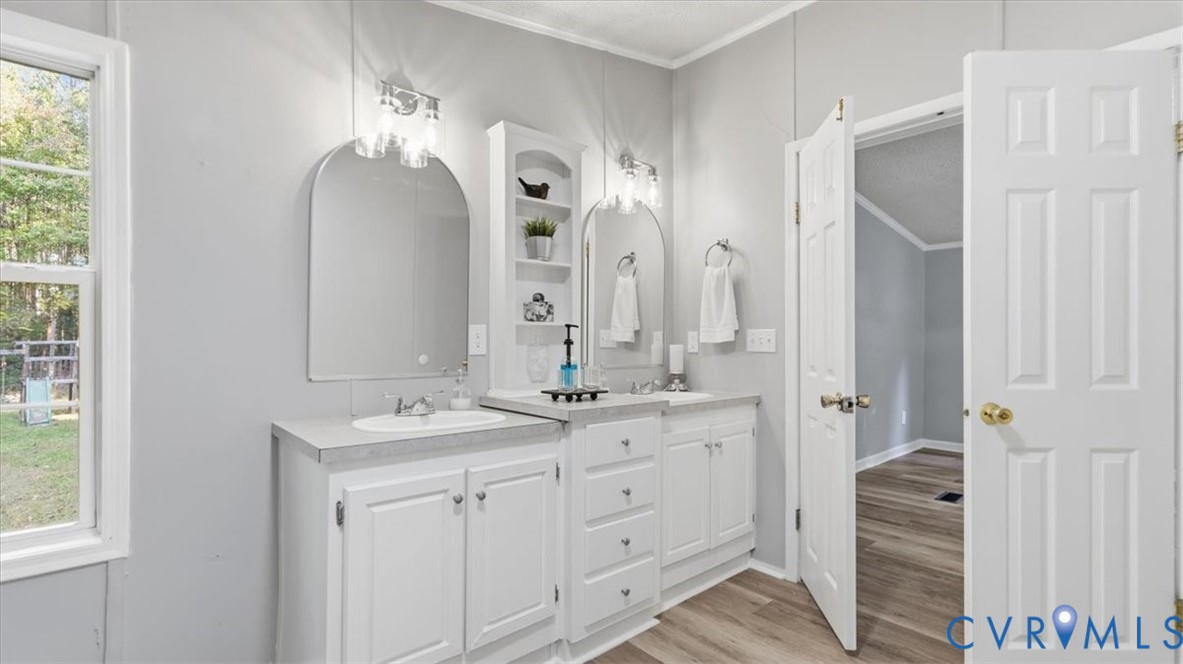 Dual-sink vanity with light-tone countertops, arched vanity mirrors, integrated shelving, and contemporary wall-mounted lighting fixtures