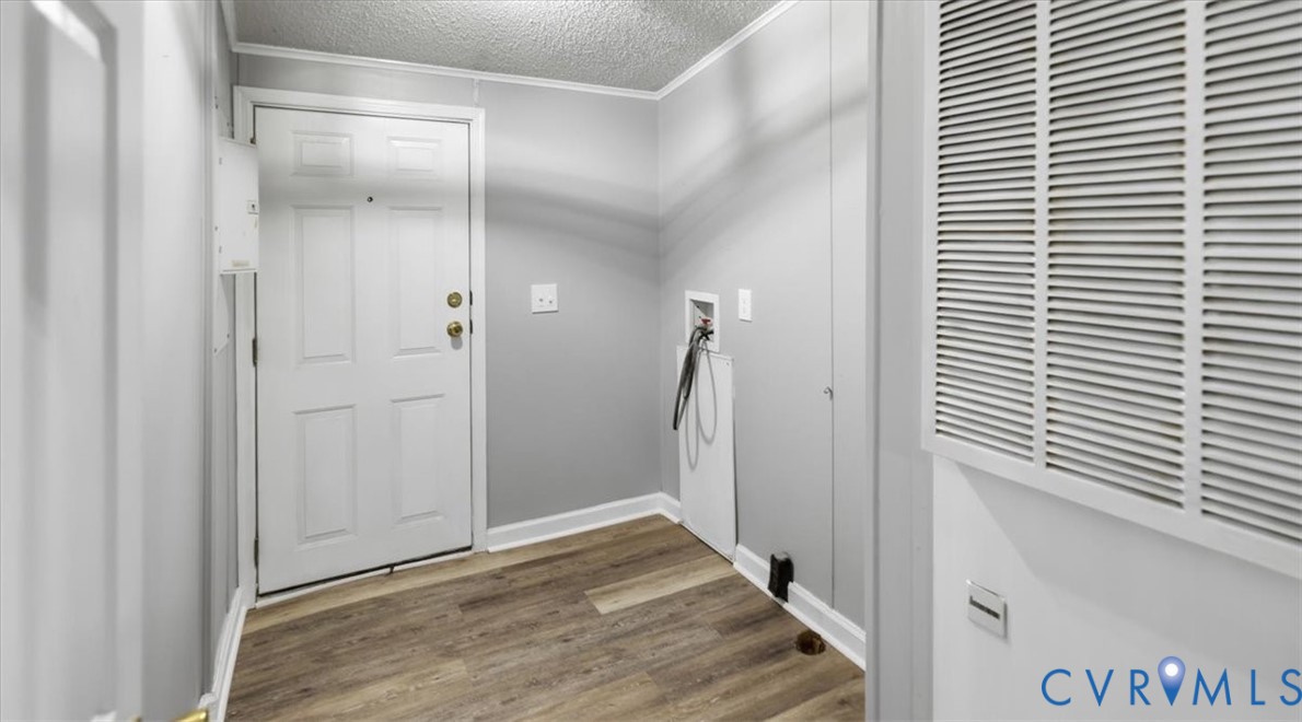 Entryway featuring wood-finish flooring, a six-panel door with metallic hardware, and dedicated utility connections