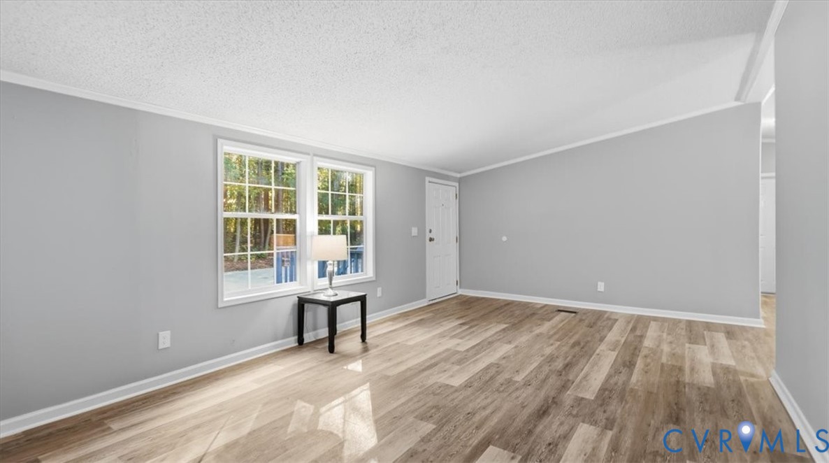 Interior space featuring wood-finish flooring, neutral wall tones, multi-pane windows, and a sloped ceiling