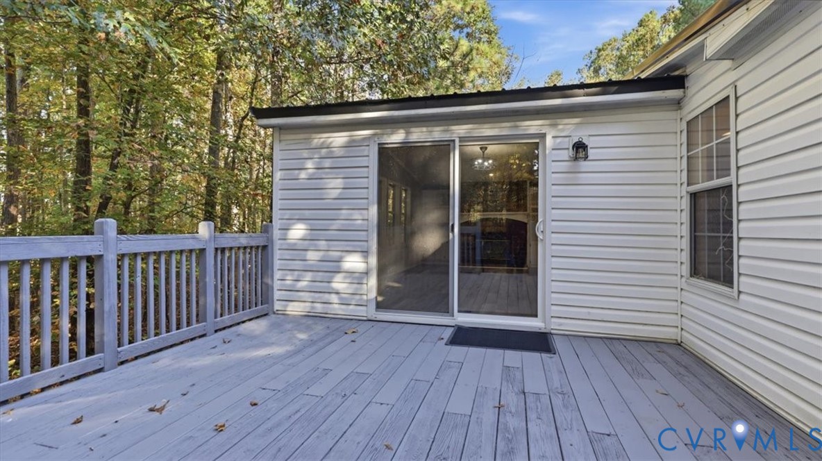Exterior deck featuring wood-finish decking, painted wooden railings, and sliding glass door access