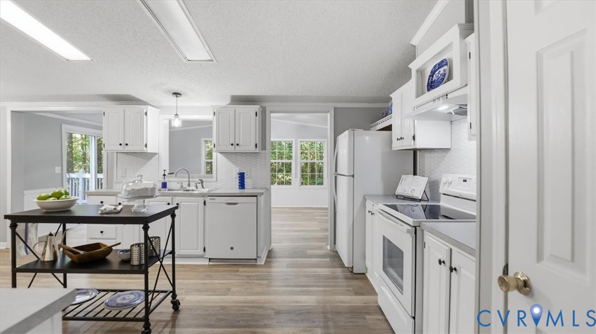 Kitchen featuring white shaker-style cabinetry, wood-finish flooring, dual-basin sink with pull-down faucet, and recessed ceiling lighting Kitchen featuring white shaker-style cabinetry, wood-finish flooring, dual-basin sink with pull-down faucet, and recessed ceiling lighting
