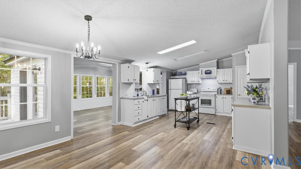 Kitchen featuring white cabinetry, light-toned countertops, wood-finish flooring, a pendant chandelier, and recessed lighting
