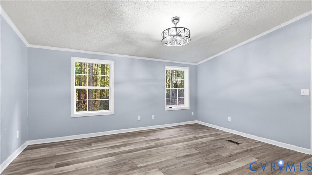 Room featuring wood-finish flooring, dual windows with exterior wooded scenery, and a modern drum-style chandelier