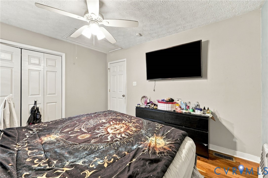Wood-finish flooring, white paneled closet doors, and white interior doors paired with a multi-blade ceiling fan featuring integrated light fixtures