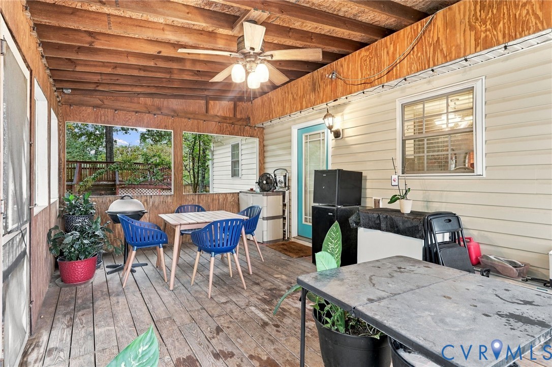 Covered porch featuring wood-plank flooring, exposed wood-beam ceiling, ceiling fan with integrated lighting, and screened-in wall segments