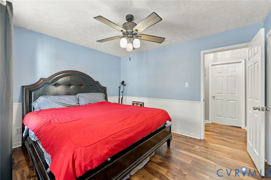 Wood-finish flooring, half-wall wainscoting, ceiling fan with integrated lighting, and multi-panel interior doors