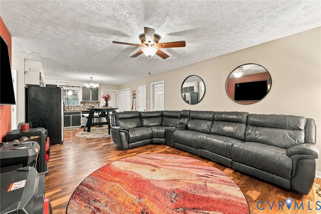 Open living area featuring wood-finish flooring, a ceiling fan with integrated lighting, and multiple interior doorways