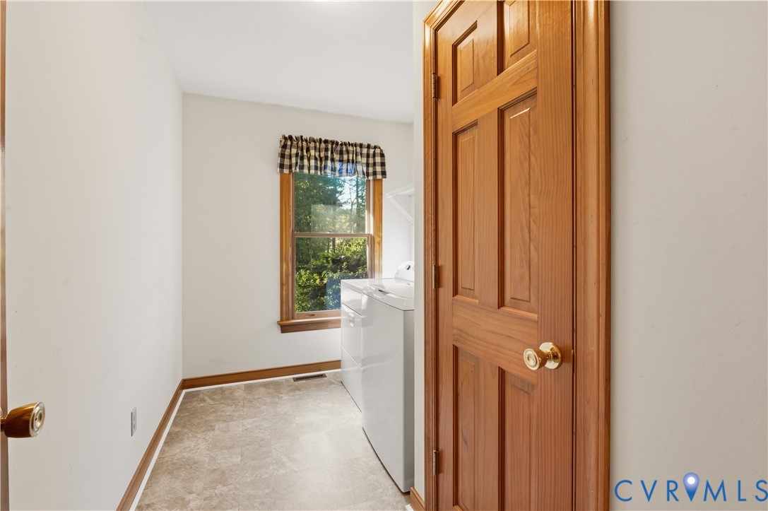 Natural-finish wood six-panel door, single-hung window with wood trim, and resilient tile flooring