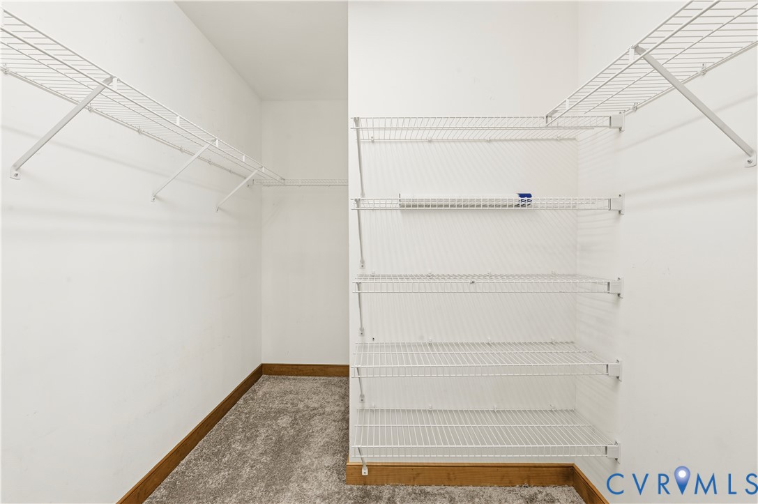 Walk-in closet featuring tiered white wire shelving and neutral carpeting