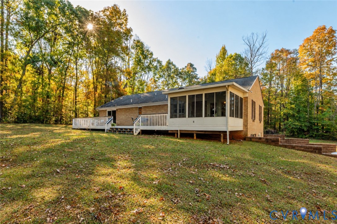 Brick exterior featuring a screened porch, expansive raised deck with white railing, and tiered masonry retaining wall