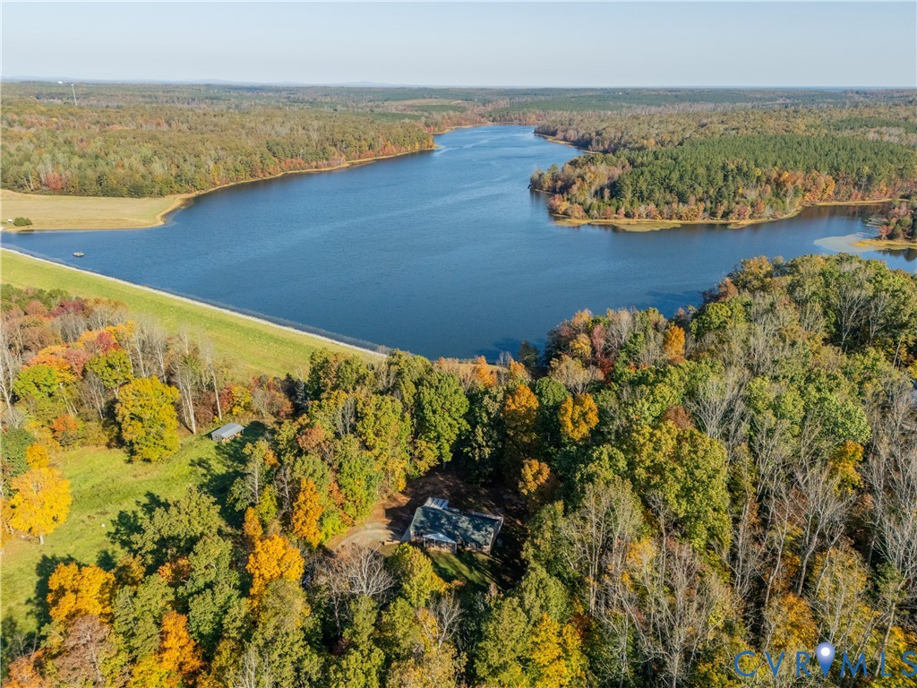 Aerial perspective featuring waterfront access, extensive wooded acreage, and natural vegetation