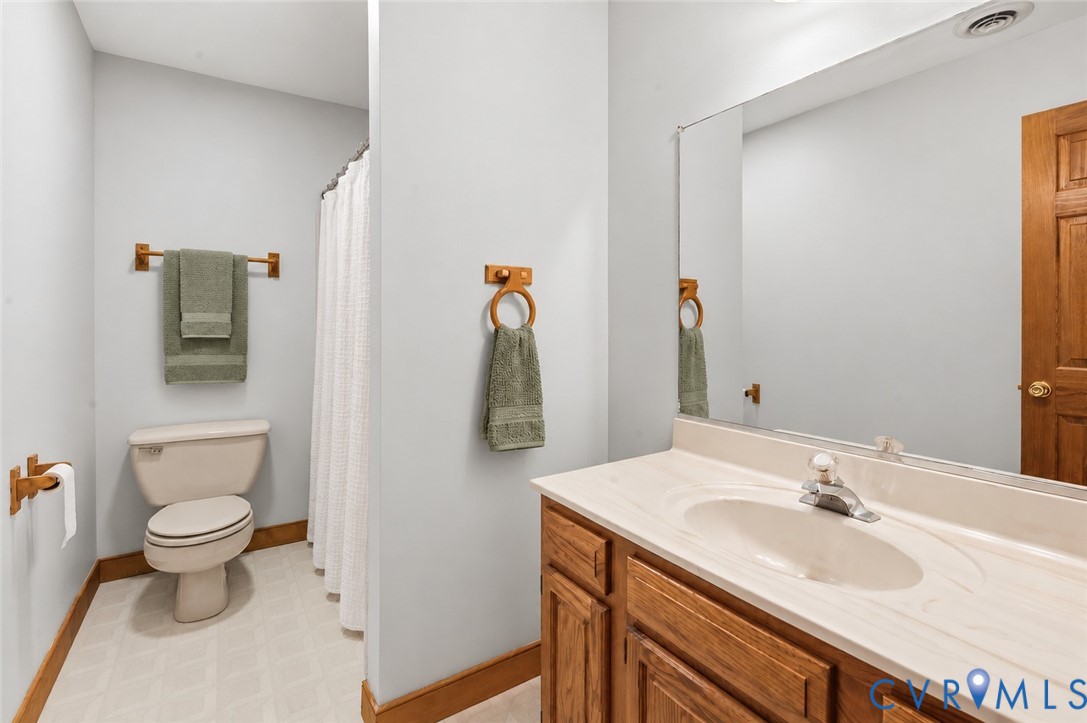 Vanity featuring a wood-finish cabinet and integrated countertop with a molded sink, large wall-mounted mirror, and combination shower and tub enclosure
