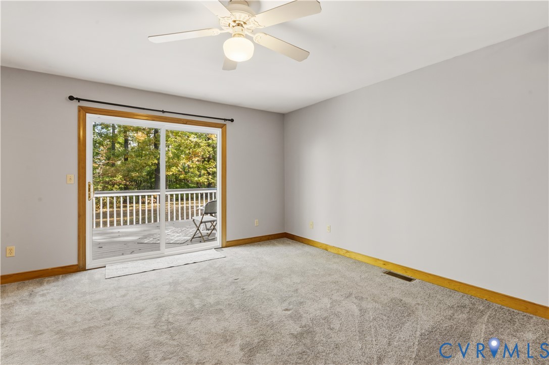 Neutral-toned carpeting, sliding glass doors with wood-finish trim, and a ceiling-mounted light fixture with a multi-blade fan