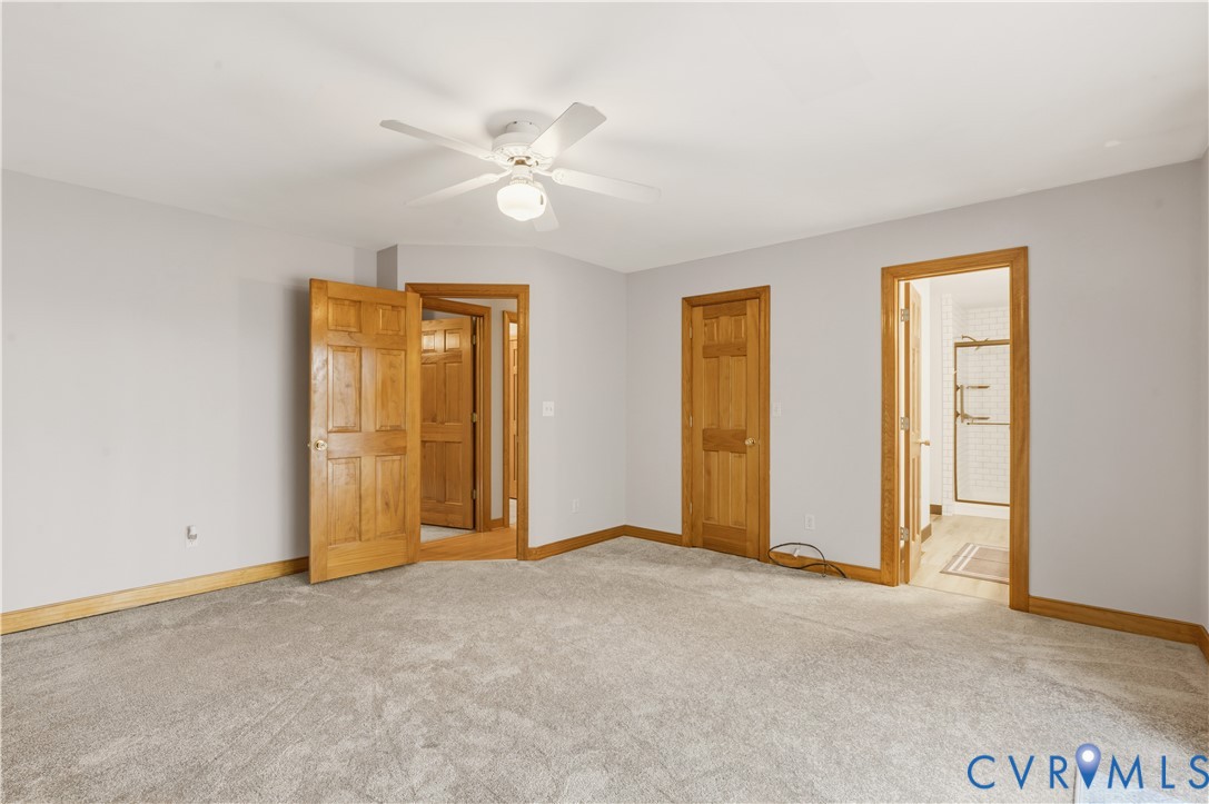 Neutral-toned carpeting, six-panel wood doors, door casings with matching wood trim, and a ceiling-mounted light fixture with integrated fan