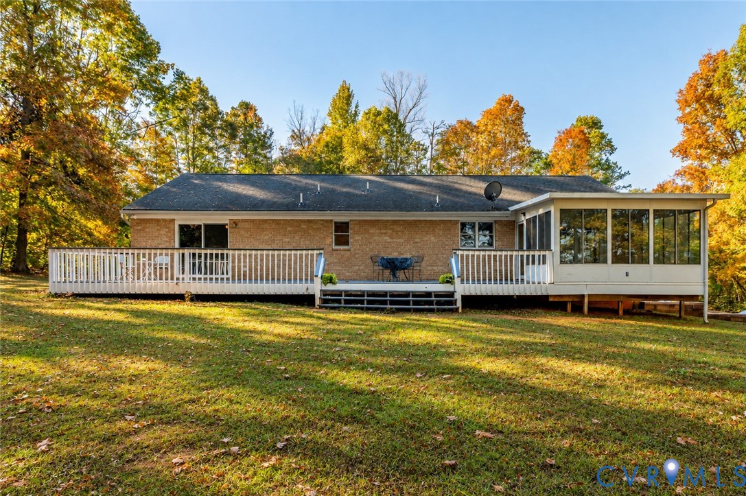 Brick exterior featuring a spacious wooden deck, screen-enclosed porch, and expansive lawn