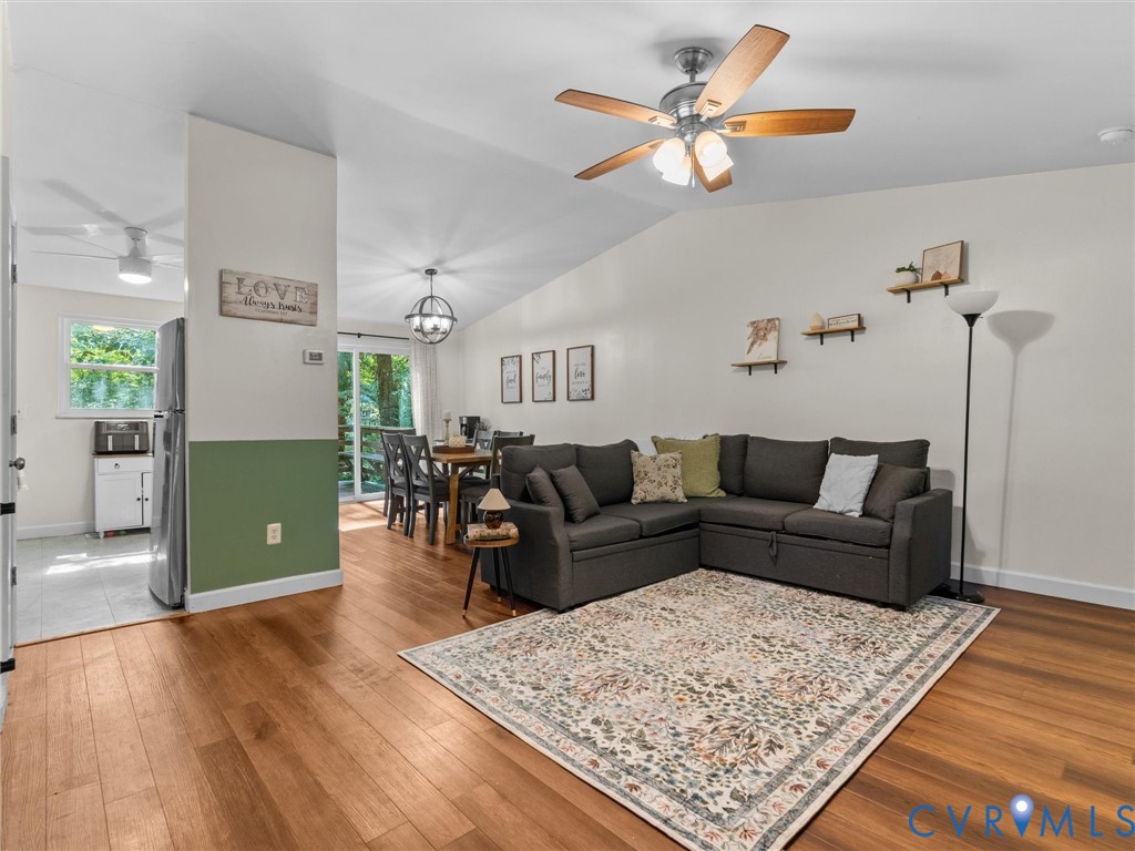Vaulted ceilings, wood-finish flooring, ceiling fan with integrated lighting, and sliding glass doors