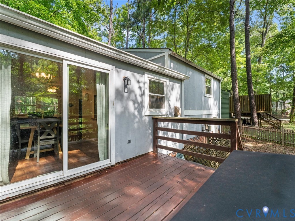 Wood deck featuring a horizontal rail, sliding glass door, and exterior wall-mounted lighting