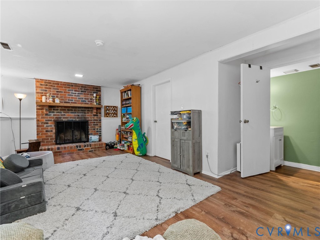 Brick fireplace with a wood mantel, wood-finish flooring, and a built-in vanity