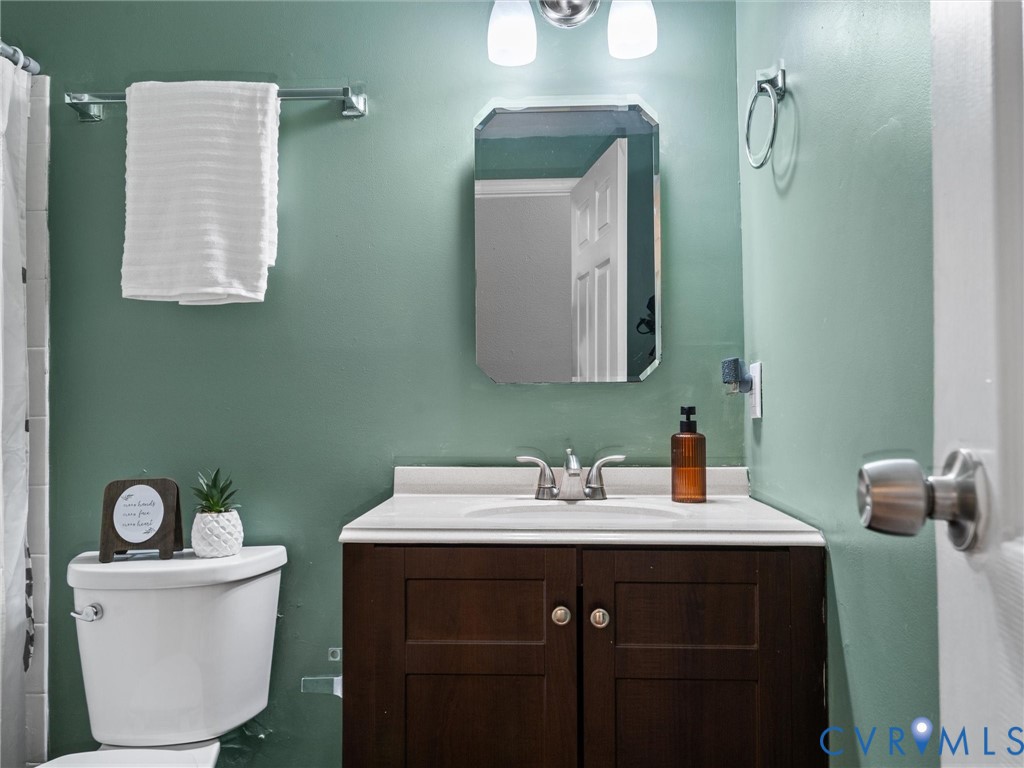 Dark wood-finish vanity with an integrated sink and countertop, polished chrome hardware, beveled wall-mounted mirror, and dual-light vanity fixture