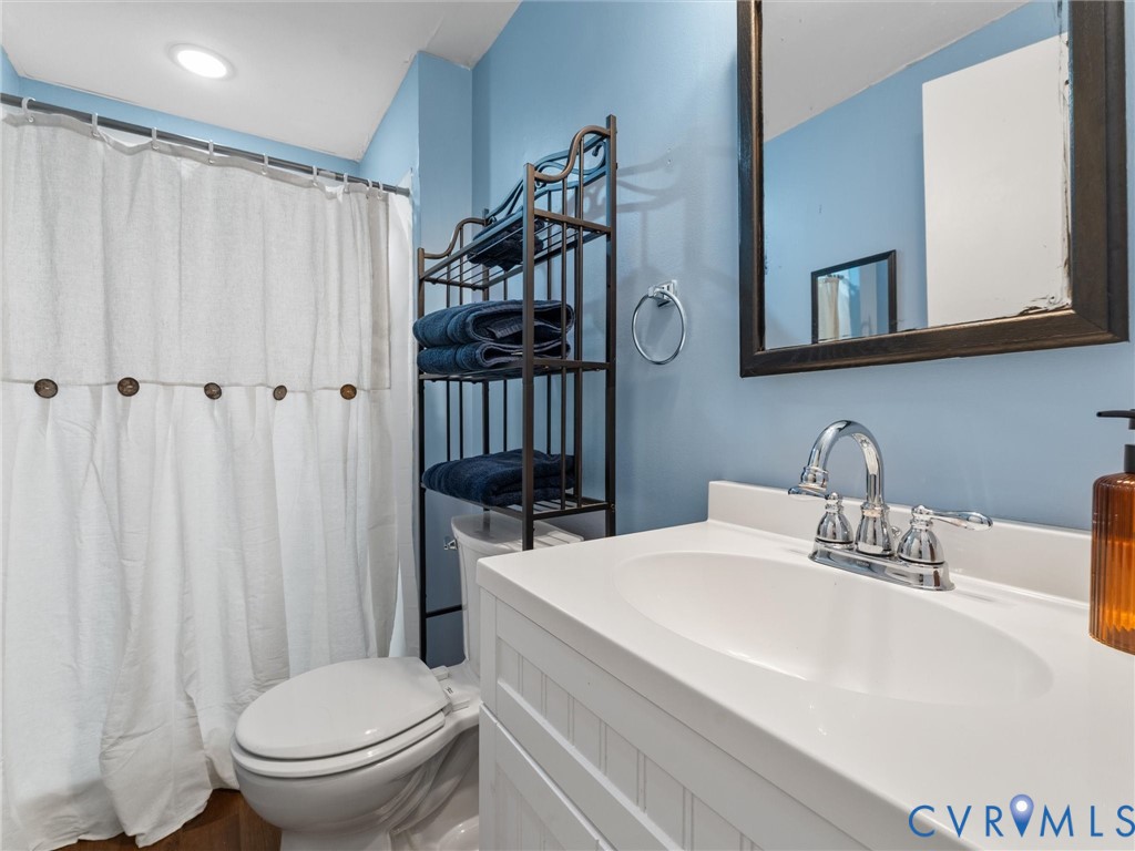 Bathroom vanity featuring a white cabinet base, integrated oval basin, and a two-handle chrome faucet