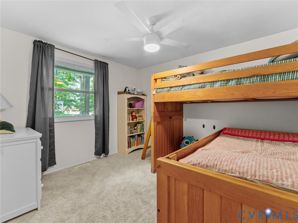 Neutral-toned room featuring wall-to-wall carpeting, a multi-blade ceiling fan with integrated lighting, and a single-pane window