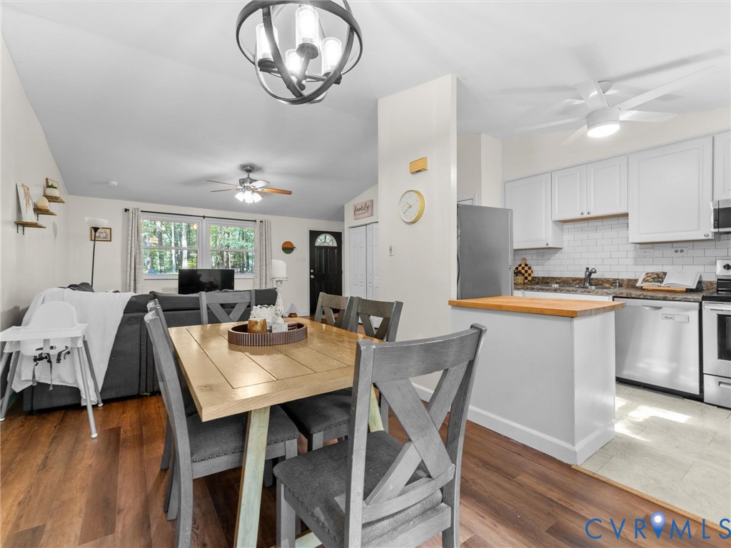 Open-concept living space featuring wood-finish flooring, white shaker-style cabinetry, subway tile backsplash, and a spherical chandelier