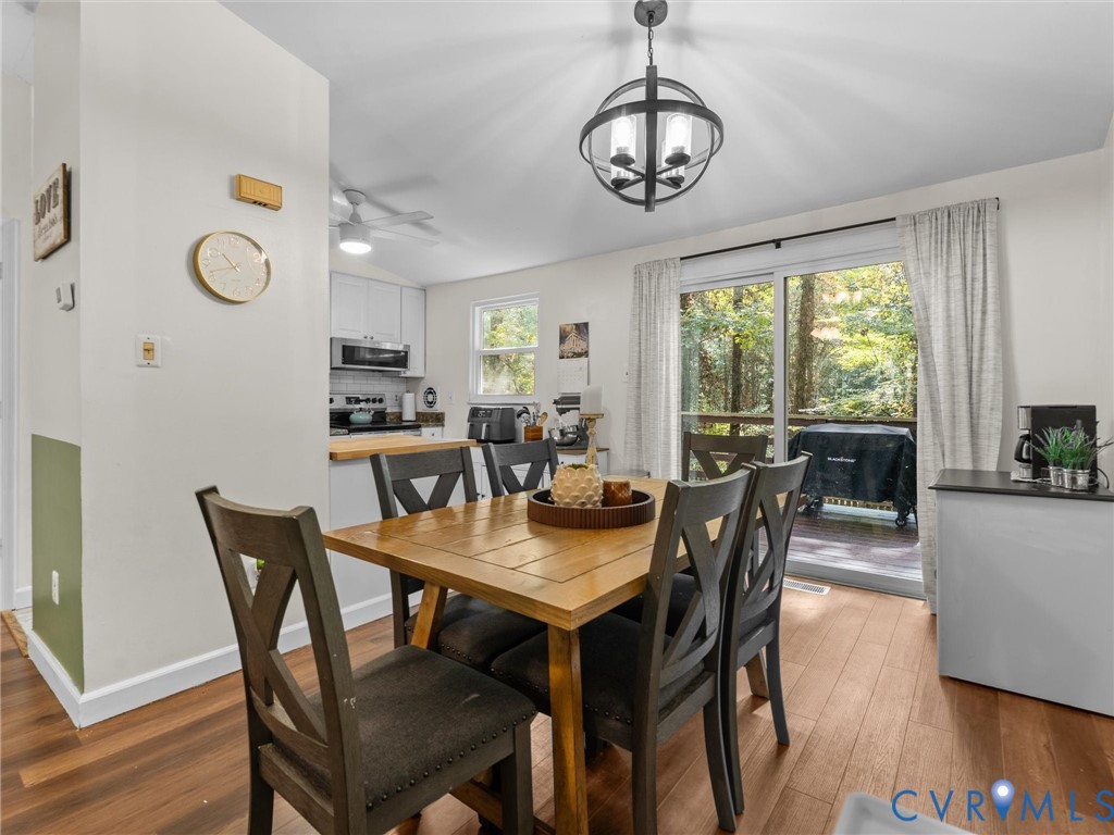 Dining area featuring wood-finish flooring, a spherical multi-light pendant fixture, and sliding glass doors with access to an exterior deck