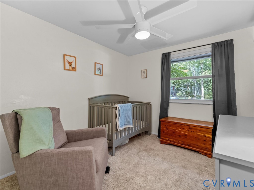 Neutral interior room featuring neutral carpeting, a white ceiling fan with integrated lighting, and a single-pane window