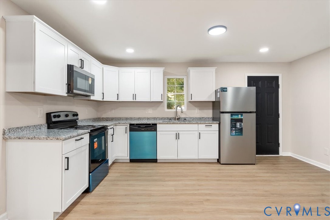 Kitchen featuring white cabinetry, stone-finish countertops, stainless steel appliances, and wood-finish flooring Kitchen featuring white cabinetry, stone-finish countertops, stainless steel appliances, and wood-finish flooring