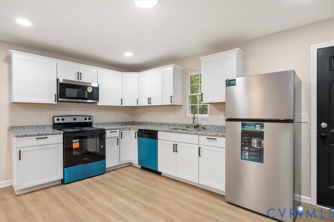 Kitchen featuring white shaker-style cabinetry, stone-finish countertops, stainless steel appliances, and wood-finish flooring Kitchen featuring white shaker-style cabinetry, stone-finish countertops, stainless steel appliances, and wood-finish flooring