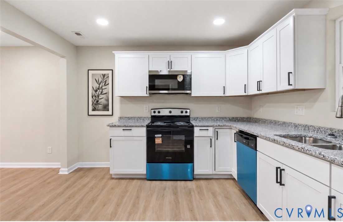 Kitchen featuring white shaker-style cabinetry, stone-finish countertops, black built-in appliances, recessed lighting, and wood-finish flooring Kitchen featuring white shaker-style cabinetry, stone-finish countertops, black built-in appliances, recessed lighting, and wood-finish flooring