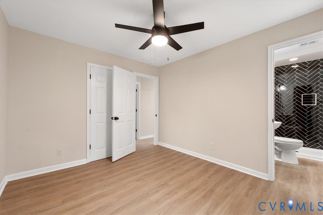 Interior space featuring wood-finish flooring, a matte black multi-blade ceiling fan with integrated lighting, and a neutral color palette